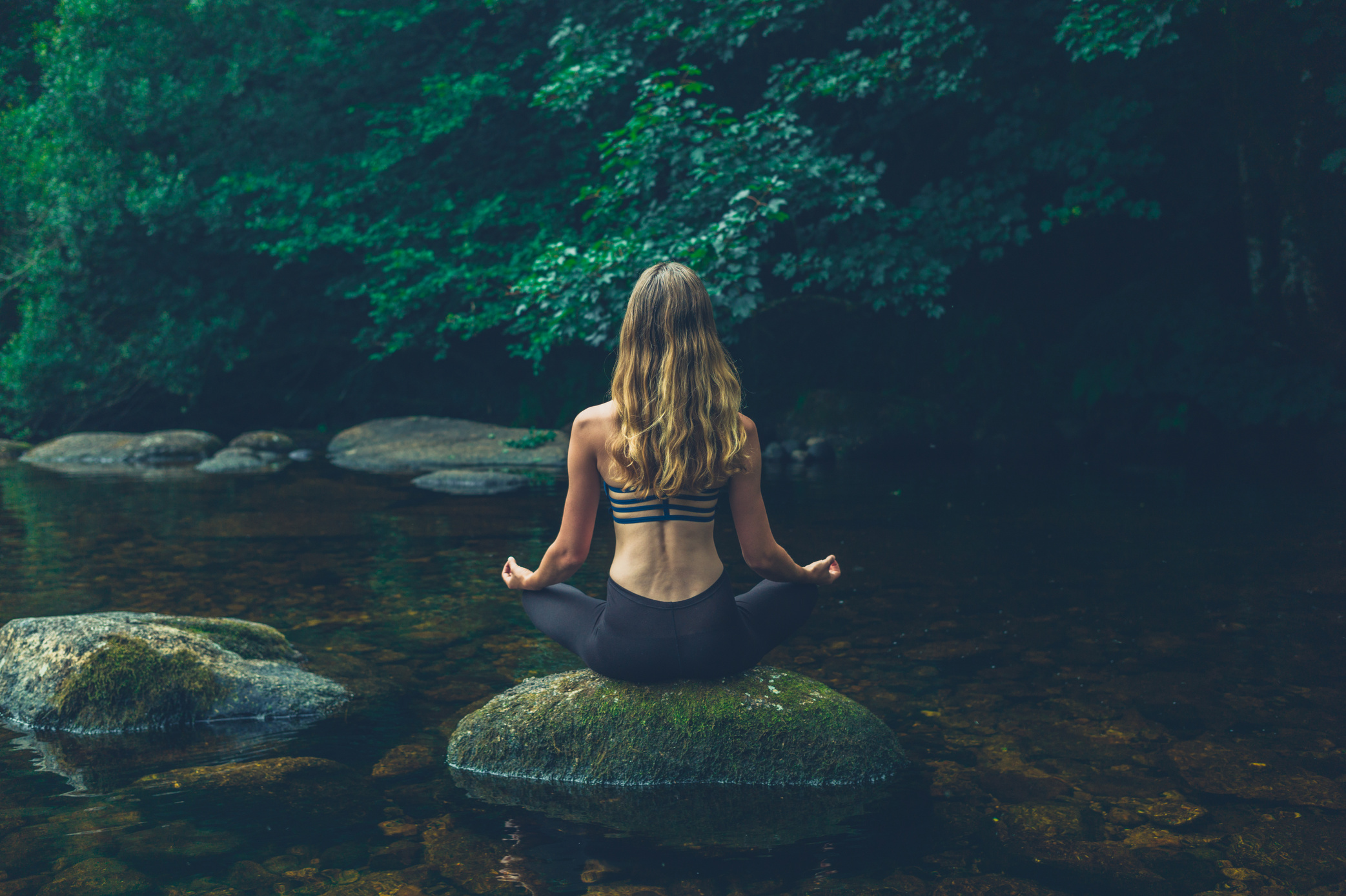 Woman Meditating on Rock in River